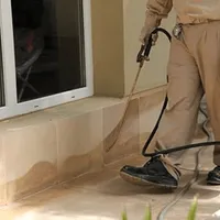 General pest control technician spraying exterior perimeter around a home in Overland Park, KS