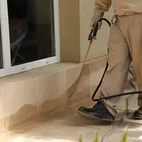 General pest control technician spraying exterior perimeter around a home in Overland Park, KS
