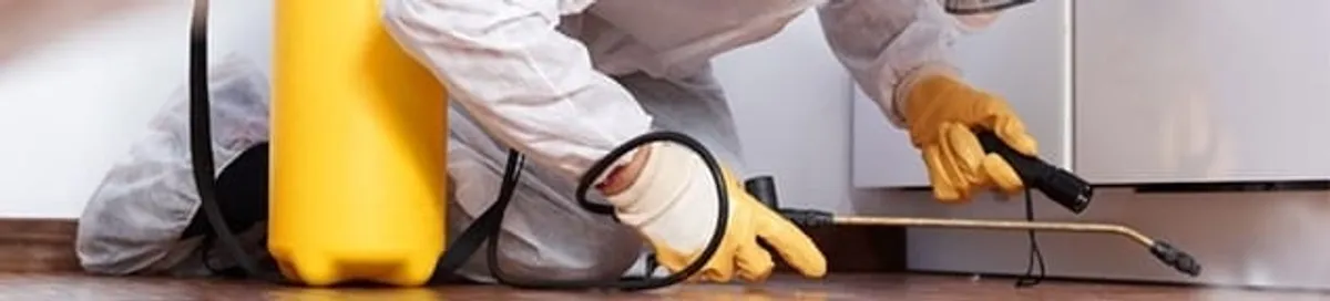 Roach exterminator treating cracks and crevices along kitchen baseboards in Overland Park, KS