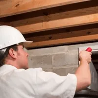 Termite inspection technician checking a basement wall and framing for termite activity in Overland Park, KS
