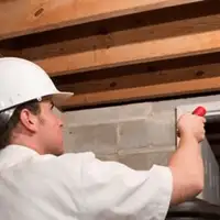 Termite inspection technician checking a basement wall and framing for termite activity in Overland Park, KS